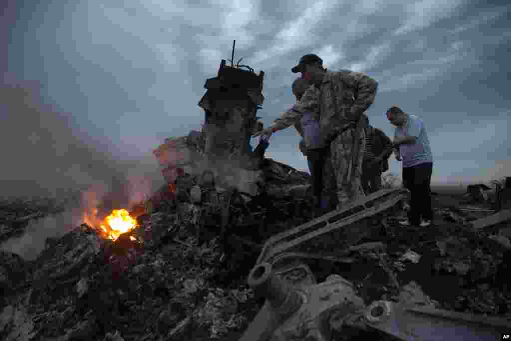 People inspect the crash site of a Malaysian Airlines Boeing 777 near the village of Grabovo, Ukraine. Ukraine said a passenger plane carrying 295 people was shot down as it flew over the country, and both the government and the pro-Russia separatists fighting in the region denied any responsibility for downing the plane.