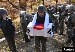 A South Korean soldier carries a casket containing a piece of bone believed to be the remains of an unidentified South Korean soldier killed in the Korean War in the Demilitarized Zone (DMZ) dividing the two Koreas in Cheorwon, South Korea, Oct. 25, 2018.