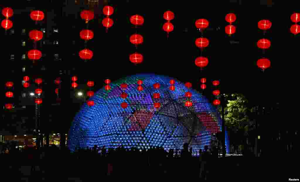 The "Rising Moon", a giant lantern, containing 7,000 recycled plastic water bottles with LED lights, measuring 20 meters in diameter and 10 meters in height, shines behind traditional Chinese lanterns at Hong Kong's Victoria Park.