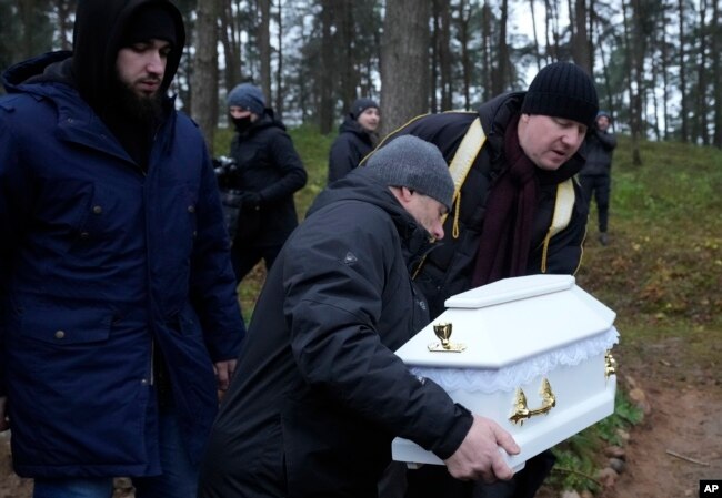 A Polish imam, right, and two other members of a Muslim community bury the tiny white casket of an unborn Iraqi boy, in Bohoniki, Poland, on Tuesday Nov. 23, 2021.