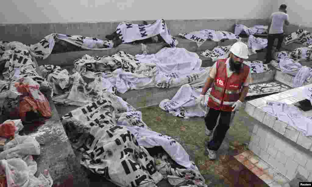 A rescue worker walks past covered bodies, killed during a fire at a garment factory, after they were brought to the Jinnah hospital morgue in Karachi, September 12, 2012.