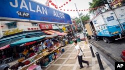A tourist walks past Malaysia's famous eatery street, Jalan Alor, a popular tourist spot in Kuala Lumpur, Malaysia on Friday, Sept. 25, 2015.