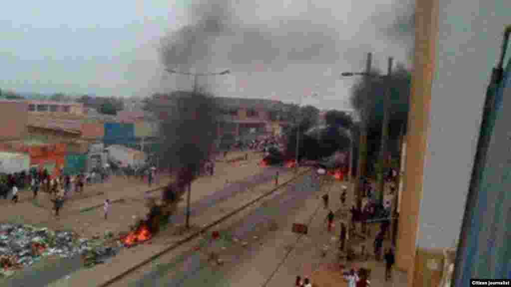 Quelques personnes marchent à pied à côté d&#39;objets en flammes sur les rues de Luanda,, 5 octobre 2015. Photo de&nbsp;​Kolly Antonio Mwanza.