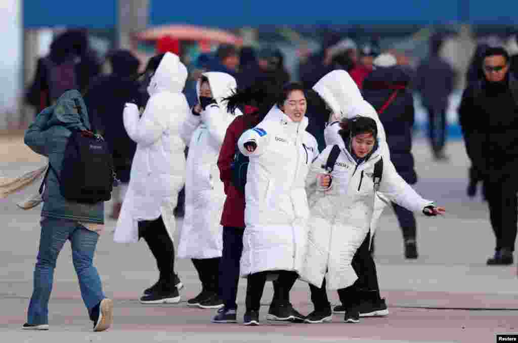 Staff from Olympic Park struggle to walk during the wind in Gangneung, South Korea.