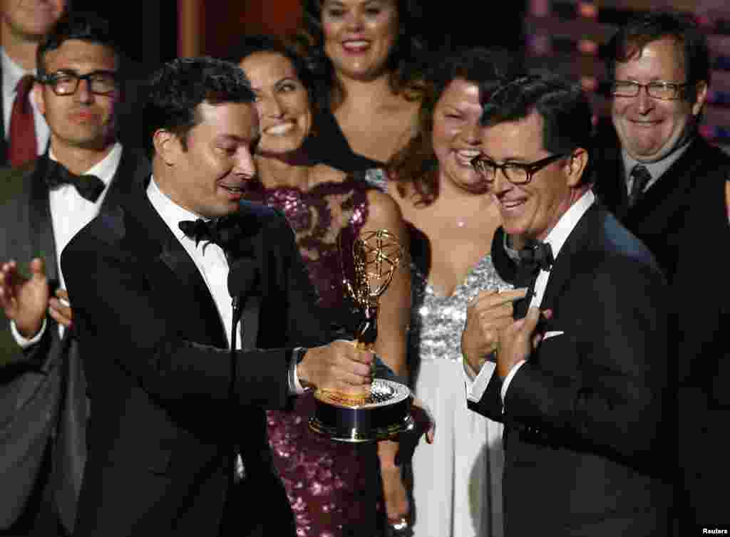 Jimmy Fallon hands off the Emmy to Stephen Colbert (right) as Colbert accepts the award for Outstanding Variety Series for Comedy Central&#39;s &quot;The Colbert Report&quot; during the 66th Primetime Emmy Awards in Los Angeles, Aug. 25, 2014.