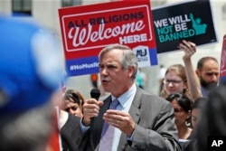 Sen. Jeff Merkley, D-Ore., speaks as protesters hold up signs and call out against the Supreme Court ruling upholding President Donald Trump's travel ban in front of the Supreme Court, June 26, 2018 in Washington.