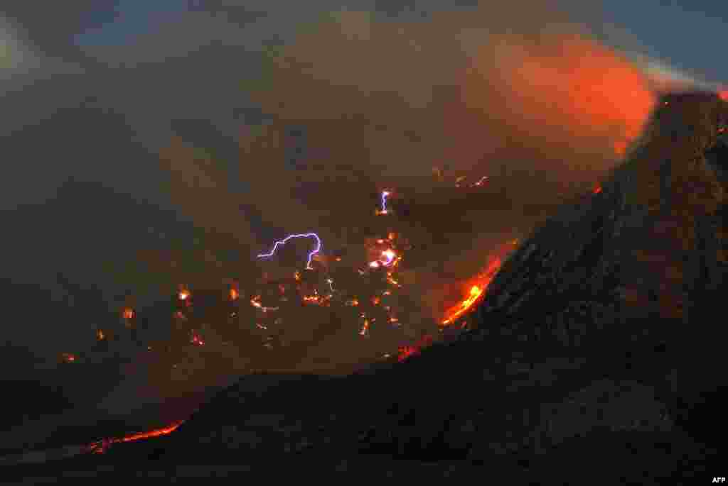 Sparks of lightning, lava flow and large clouds of ash are released from the crater during the eruption of Mount Sinabung volcano, as seen from Karo district located in Sumatra island, Indonesia. 