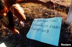 A member of indigenous Munduruku tribe is seen near a placard as they occupy the construction site of the hydropower plant of Sao Manoel, near the Teles Pires river, in the Alta Floresta city, in the north of the state of Mato Grosso in the Amazon, Brazil, July 16, 2017. The placard reads: ' The government doesn't consult the indigenous peoples.'