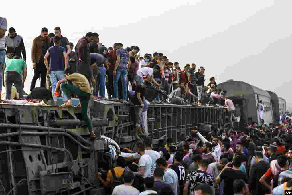 People climb an overturned train carriage as they gather at the scene of a railway accident in the city of Toukh in Egypt&#39;s central Nile Delta province of Qalyubiya, April 18, 2021.