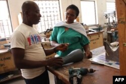 Les orthopédistes togolais font les derniers ajustements au support prothétique imprimé en 3D pour Adjovi Koudahe au CNAO de Lomé, le 19 juin 2018.