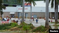 Warga setempat harus melewati jalanan yang terendam banjir setelah berbelanja dari sebuah pusat pertokoan di Acapulco, Meksiko (17/9). Sedikitnya 47 orang dilaporkan tewas dan 40 ribu orang wisatawan terlantar pasca hantaman badai tropis Manuel di kawasan tersebut.