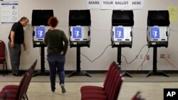 FILE - Kelly Monroe, investigator with the Georgia Secretary of State office (L) takes a look at a new voting machine that produces a paper record being tested at a polling site in Conyers, Ga.