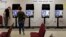 FILE - Kelly Monroe, investigator with the Georgia Secretary of State office (L) takes a look at a new voting machine that produces a paper record being tested at a polling site in Conyers, Ga.