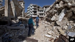 Des enfants syriens marchent entre les bâtiments détruits dans la vieille ville de Homs, en Syrie, le 26 février 2016. (AP Photo/Hassan Ammar) 