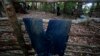 A Thai Border patrol police officer walks behind a pair of jeans left at abandoned migrant camp on Khao Kaew Mountain near the Thai-Malaysian border in Padang Besar, Songkhla province, southern Thailand, Tuesday, May 5, 2015. Police have found a recently 