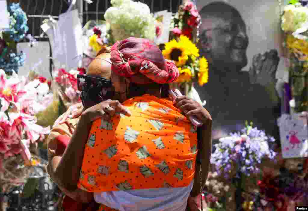 Joy Ngoma, granddaughter of late Archbishop Desmond Tutu, embraces a family member in front of a remembrance wall, outside the St. Georges Cathedral, in Cape Town, South Africa, Dec. 31, 2021.