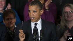 President Barack Obama holds up a pen as he speaks about the economy and the deficit in the East Room of the White House in Washington, November 9, 2012.