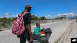 Un hombre empuja a un niño en una carretilla en Pont-Sonde, Haití, el 7 de octubre del 2024, días después de una matanza en esa área.