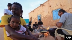 FILE - People sit around food cooking on a bonfire at a school that has been transformed into a shelter for people displaced by conflict in Sudan's northern border town of Wadi Halfa near Egypt on September 11, 2023.