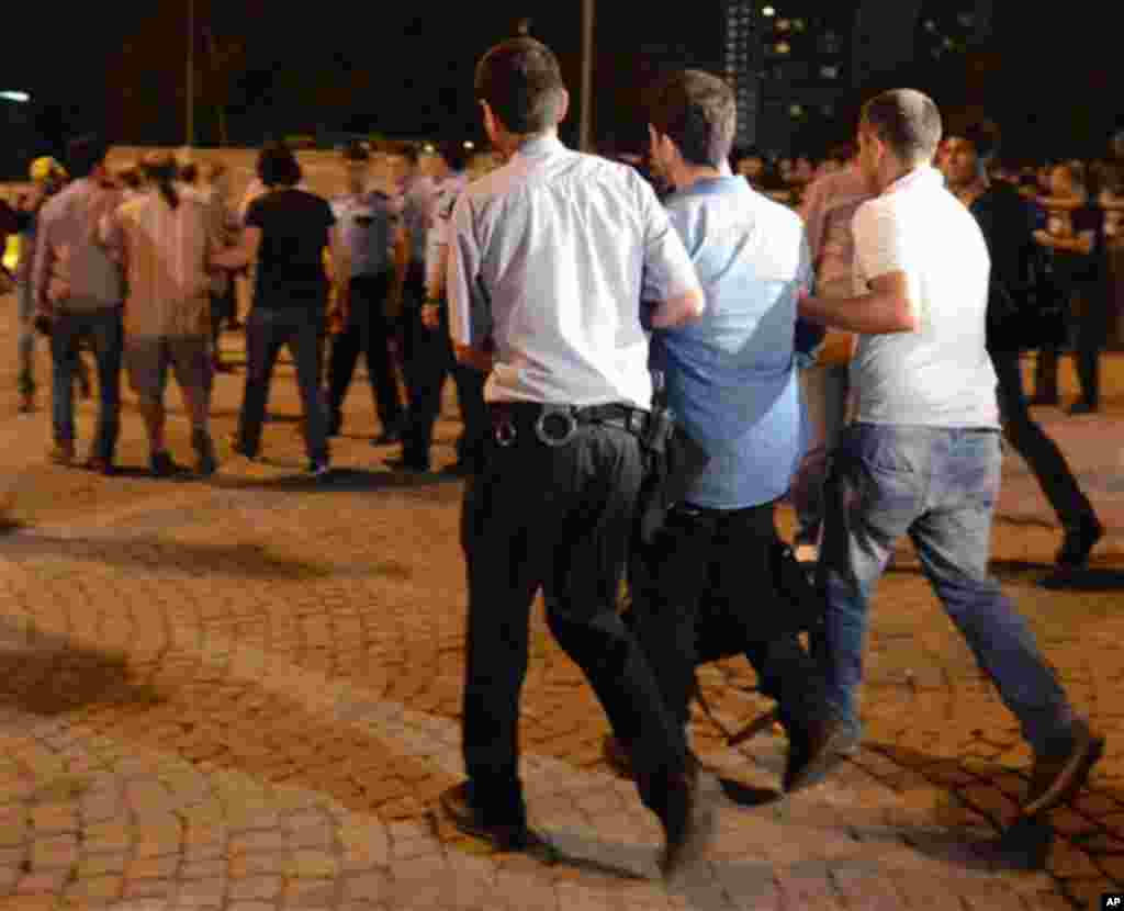 Plaincloth police officers detain people, during a silent protest on Taksim Square in Istanbul, Turkey, early Tuesday, June 18, 2013. After weeks of confrontation with police, sometimes violent, Turkish protesters are using a new form of resistance: stand