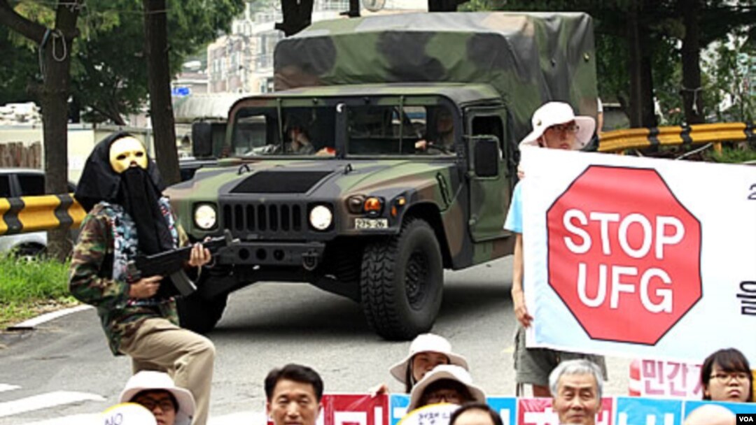 Warga Korsel memprotes latihan militer bersama AS-Korsel di Seongnam, bagian Selatan Korea Selatan, sementara kendaraan militer AS melaju di dekatnya (16/8)