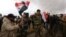 Syrian volunteers and relatives wave the national flag and portraits of President Bashar al-Assad as they celebrate at the end of paramilitary training conducted by the Syrian army in al-Qtaifeh, near Damascus, Feb. 22, 2016.