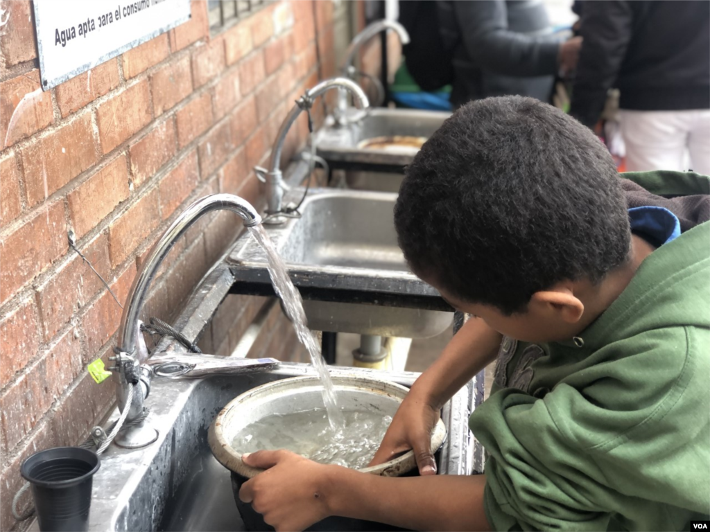 Un niño lava una olla en una estación de lavamanos instalada por las autoridades de Colombia para los migrantes. Una ventaja en este momento ya que el municipio de Ipiales no tiene agua desde el mes pasado debido a problemas con el acueducto. Ipiales, Colombia, 11 de septiembre de 2019. Foto: Celia Mendoza - VOA. 