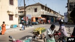 Un vendeur d'oranges accueille un ami devant un vieux bâtiment colonial dans le centre de Ziguinchor, le 11 février 2021.