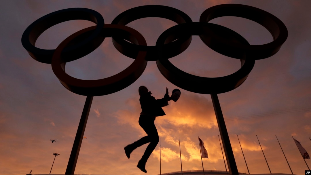 Một người phụ nữ chụp hình cùng những vòng tròn biểu tượng Olympic.