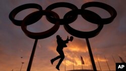 Một người phụ nữ chụp hình cùng những vòng tròn biểu tượng Olympic.