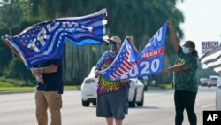 Archivo - Partidarios del presidente Donald Trump y el exvicepresidente demócrata Joe Biden ondean banderas mientras esperan que llegue la caravana de Biden, el 13 de octubre de 2020, en el Parque Regional Miramar en Miramar, Florida.