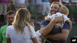 Dustin Johnson, right, greets his fiancée Paulina Gretzky as he holds their son Tatum Gretzky on the 18th hole during the final round of the U.S. Open golf championship at Oakmont Country Club on Sunday, June 19, 2016.