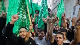 Filistinliler Gazze'de hastanenin vurulmasının ardından ellerinde Hamas bayraklarıyla işgal altındaki Batı Şeria'da protesto gösterisinde, 17 Ekim 2023. 