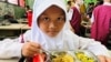 A girl begins her free meal of rice, chicken, tofu, stir-fried corn and watermelon. (Devianti Faridz/VOA)