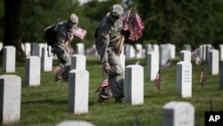 Dua tentara AS menempatkan bendera AS di taman makam pahlawan Arlington menjelang peringatan Hari Pahlawan (23/5).