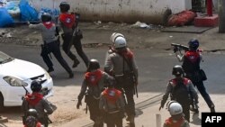 FILE - Police chase after protesters as they crack down on demonstrations against the military coup in Yangon, Myanmar, Feb. 27, 2021.