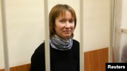 Yekaterina Zaspa, one of the 30 people who were arrested over a Greenpeace protest at the Prirazlomnaya oil rig, looks out from a defendants' cage as she attends a court session in St. Petersburg, Nov. 18, 2013.