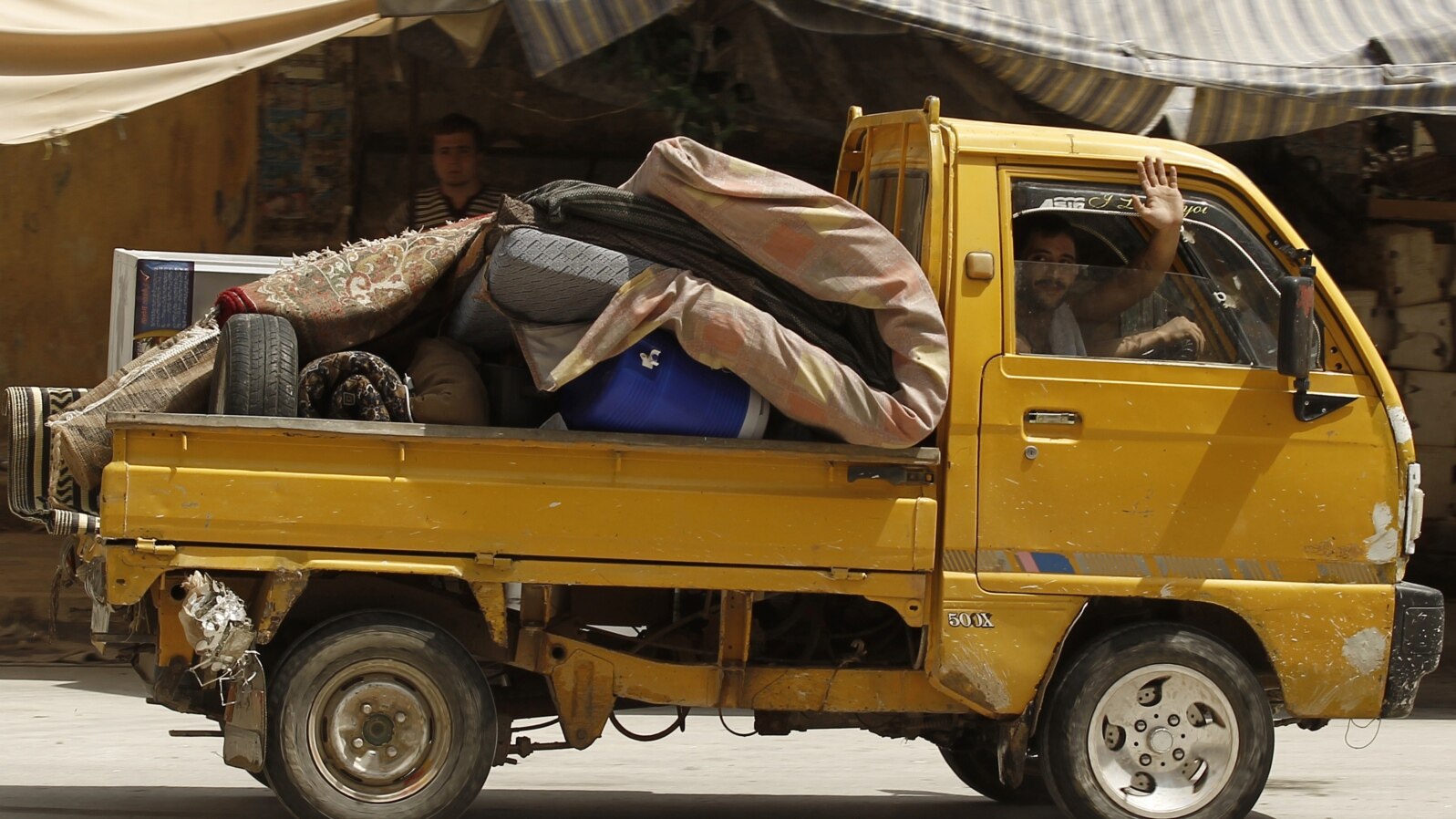 A man waves as he flees Aleppo, July 29, 2012. 