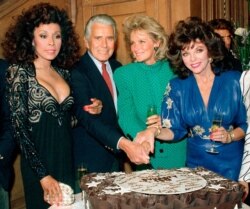 FILE - Diahann Carroll, John Forsythe, Linda Evans and Joan Collins from "Dynasty" cut a cake to commemorate the production of 150 episodes of the show in Los Angeles, Sept. 24, 1986.