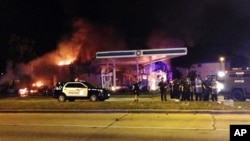 Authorities respond near a burning gas station as dozens of people protest following the fatal shooting of a man in Milwaukee, Aug. 13, 2016. 