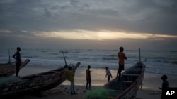 Jóvenes senegaleses se reúnen al atardecer alrededor de piraguas en la playa en Fass Boye, Senegal, el martes 29 de agosto de 2023