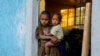 FILE - An 11-year-old girl holds her year-old brother at the doorway to a classroom now used as living space at the Tsehaye primary school, which housed people displaced by conflict, in Shire, Tigray region, Ethiopia, March 15, 2021.