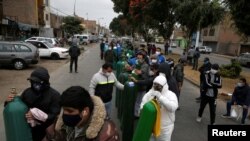 Ciudadanos en Lima, Perú, usando máscaras faciales esperan a rellenar los balones de oxígeno cuando la crisis de coronavirus continúa azotando al país.
