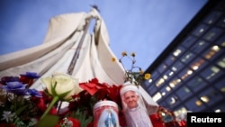 Una vela con una imagen del Papa Francisco se encuentra junto a la estatua del fallecido Papa Juan Pablo II, afuera del Hospital Gemelli, donde el Papa Francisco está ingresado para recibir tratamiento, en Roma, Italia, el 20 de febrero de 2025.