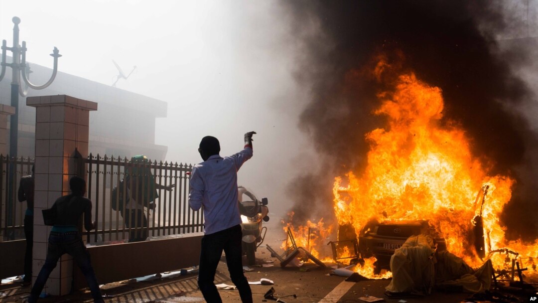Mobil dibakar di luar gedung parlemen di tengah kerusuhan di Ouagadougou, Burkina Faso, Kamis (30/10). (AP/Theo Renaut)