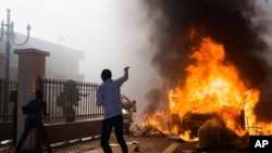 Mobil dibakar di luar gedung parlemen di tengah kerusuhan di Ouagadougou, Burkina Faso, Kamis (30/10). (AP/Theo Renaut)