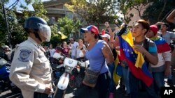 Demonstran meneriakkan slogan-slogan anti-pemerintah sementara polisi menghalangi akses ke pusat kota Karakas, Venezuela (24/1). (AP/Ariana Cubillos)