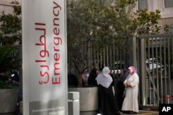 Families of victims who were injured on Tuesday by their exploding handheld pagers, wait at the emergency entrance of the American University hospital, in Beirut, Sept. 18, 2024.