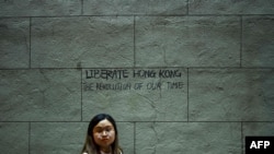 A pro-democracy protester walks past graffiti on a wall in Hong Kong, Aug. 16, 2019. Hong Kong's pro-democracy movement faces a major test this weekend as it tries to muster another huge crowd following criticism over a recent violent airport protest. 