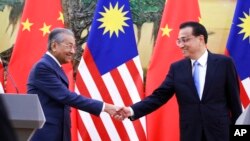 Perdana Menteri Malaysia Mahathir Mohamad (kiri) berjabat tangan dengan Perdana Menteri China, Li Keqiang di Balai Rakyat China, Beijing, 20 Agustus 2018. 